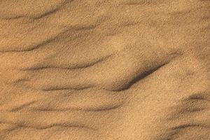 Texture of sand in the desert close-up background. A dune with a pattern of sand waves photo