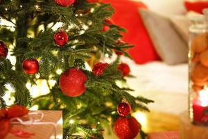 decoración navideña roja en el árbol de navidad con guirnaldas de luces. año nuevo, elementos de decoración del hogar. espacio para texto foto