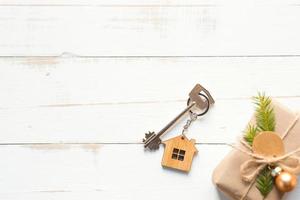 The key to the house on a natural background with a box with a gift for Christmas and new year. Eco-friendly housing, mortgage, loan, booking, purchase of real estate, moving into your home photo