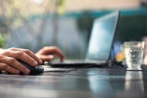 Working at a laptop in the outdoor courtyard - men's hands close-up. Home office, remote work, remote location. Using the keyboard and mouse, relax photo