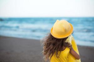 una niña con un círculo inflable amarillo en la orilla del mar. relajarse en la playa, viajes de verano. foto