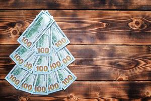 Christmas tree made of 100 dollar bills on wooden background with copyspace. Christmas decor on theme of finance, savings, wealth, expenses in new year. Flatly. Stack of  100, Investments, business photo