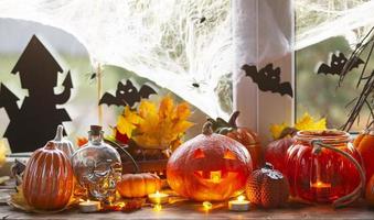 Festive decor of the house on the windowsill for Halloween - pumpkins, Jack o lanterns, skulls, bats, cobwebs, spiders, candles and a garland - a cozy and terrible atmosphere photo