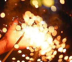 Sparks and light from sparklers in the dark on the palm of a person. Christmas magic, new year's eve, festive background. Space for text photo