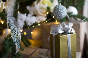 caja de regalo en embalaje dorado y lazo plateado bajo el árbol de navidad  con decoración blanca. año nuevo, nochebuena, saludos para la familia,  consuelo y esperando un milagro 9966158 Foto de