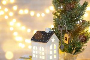 Key to the house with a keychain on a table with a Christmas decor. A gift for New Year, Christmas. Building, design, project, moving to new house, mortgage, rent and purchase real estate. Copy space photo