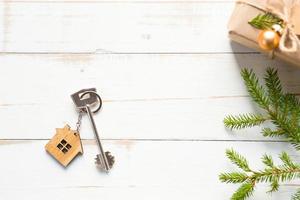 The key to the house on a natural background with a box with a gift for Christmas and new year. Eco-friendly housing, mortgage, loan, booking, purchase of real estate, moving into your home photo