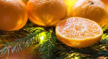 Fresh tangerines in garland lights, on fir branches and tinsel - new year's bright background. Half of an orange, citrus aroma of the holiday. Christmas, New year. Space for text. photo