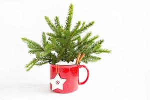 ramo de navidad en una taza roja hecha de abeto vivo y decoraciones y accesorios festivos, juguetes para el árbol de navidad, dulces. año nuevo, humor festivo, floristería en un fondo blanco foto