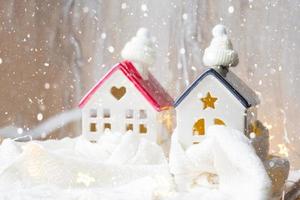 Cozy house is wrapped in a hat and scarf in a snowstorm -window sill decor. Winter, snow - home insulation, protection from cold and bad weather, room heating system. Festive mood, Christmas, New Year photo