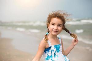 retrato de una niña en la orilla del mar. el niño disfruta de las olas, relajarse en la playa, viajar. foto