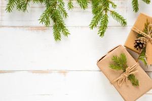 caja de regalo para navidad y año nuevo en materiales ecológicos papel kraft, ramas de abeto vivas, conos, hilo. etiquetas con maqueta, decoración natural, hechas a mano, bricolaje. planamente, fondo, marco, minimalismo foto