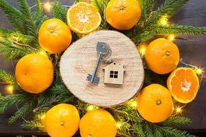 New year's background with keys to new house on round cut of tree by tangerines, live fir branches and lights garlands. Transfer, shares of the mortgage, the rental of a cottage. aroma Christmas. photo