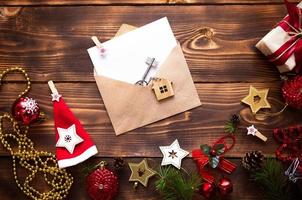 Christmas flat lay on a wooden background with keys to new house in the center with a envelope with a note sheet. New year, transfer, shares of the mortgage, the rental of a cottage. Space for text photo