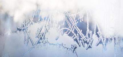 Frost pattern on the window glass. White frost with a blue tinge on a frosty day. Winter, an ornament of nature. Banner, space for text photo