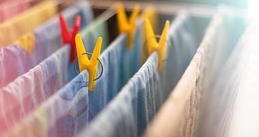 Colorful clean bed linen and towels after washing are hung on the bars of the dryer and secured with yellow and red clothespins. General cleaning, Laundry drying, compact dryer for the house. photo