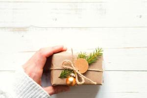 Gift box for Christmas and new year in eco-friendly materials kraft paper, live fir branches, cones, twine. Tags with mock up, natural decor, hand made, DIY. Flatly, background, frame, Minimalism photo