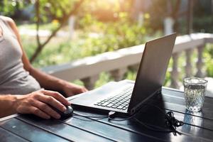 Working at a laptop in the outdoor courtyard - men's hands close-up. Home office, remote work, remote location. Using the keyboard and mouse, relax photo