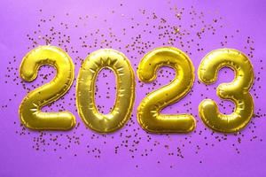 Happy New Year- golden numbers 2023 on a purple background with sequins, stars, glitter, lights of garlands. Greetings, postcard. Calendar, cover. photo