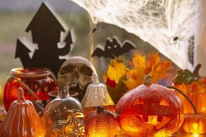 Festive decor of the house on the windowsill for Halloween - pumpkins, Jack o lanterns, skulls, bats, cobwebs, spiders, candles and a garland - a cozy and terrible atmosphere photo