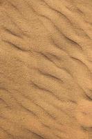 Texture of sand in the desert close-up background. A dune with a pattern of sand waves photo