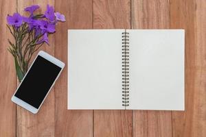 top view notebook, smartphone and flower on wooden table. photo