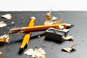 Broken pencil with metal sharpener and shavings on black background. Horizontal image. photo