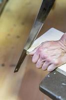 man sawing a board with a hacksaw photo