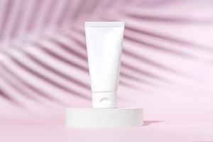 crema para la cara o la mano en un tubo de plástico blanco sobre un fondo rosa con sombra de una palmera tropical. accesorio cosmético femenino para maquillaje. maqueta, identidad, espacio de copia foto