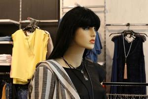 A mannequin stands on a showcase in a large store. photo