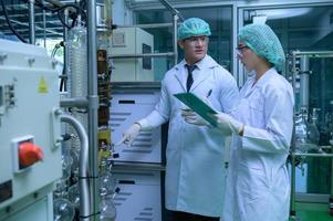 Scientists and assistants are in the machine room extracting oil and cannabis seeds. Inspecting cannabis oil extractor before starting to extract the prepared cannabis photo