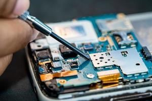 Technician repairing inside of mobile phone by soldering iron. Integrated Circuit. the concept of data, hardware, technology. photo