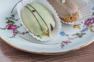 eclairs franceses en plato de porcelana de colores sobre mesa de madera. foto