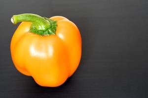 orange bell pepper on black background, copy space for your text photo