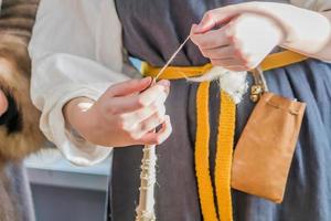 woman in traditional russian clothes weaves a spindle photo