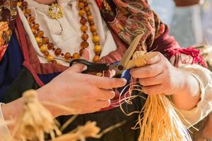 mujer en ropa tradicional rusa haciendo muñeca de paja foto