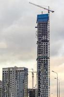 Grúa y obra de construcción contra el cielo nublado foto