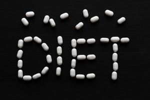 Medical concept written with pills word DIET On black wooden background with copy space photo