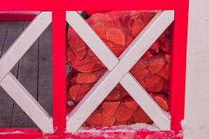 un haz de leña detrás de una valla de madera roja foto