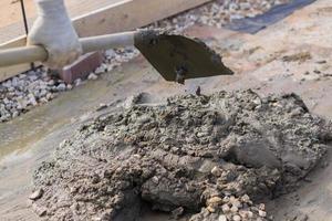 worker mixing concrete and gravel with spade on construction cite photo