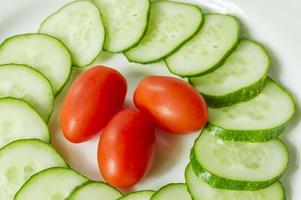 cucumbers and cherry tomatoes on a white plate photo