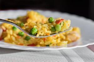 paella with chicken and seafood on white plate. photo