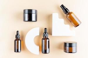 Trendy presentation of cosmetic set for skin care. Top view of dark glass packaging - dropper bottle, cream jar and bottle dispencer fith essence on concrete poduims. photo