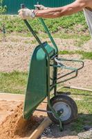 man holding wheelbarrow for transporting sand photo