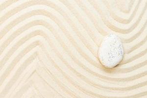 piedra blanca en la arena del mar. fondo de jardín japonés zen. vista superior con espacio de copia foto