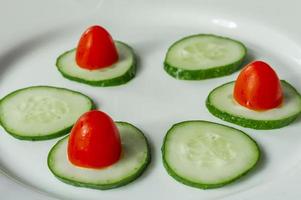 cucumbers and cherry tomatoes on a white plate photo