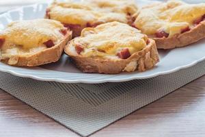 close-up of baked hot sandwiches with cheese and sausage on white plate photo