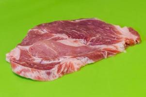 Raw pork steak on green background photo