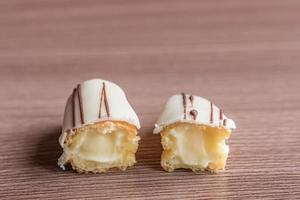 Two halves of Eclair with glaze on a wooden table photo