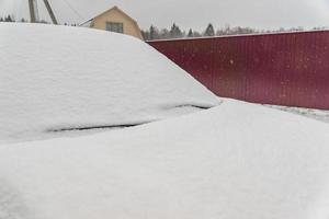 coche cubierto de nieve sobre fondo de valla metálica foto